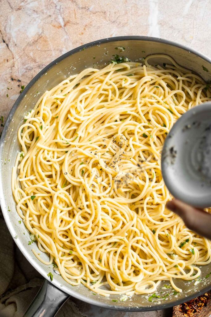 Seasoning lemon butter pasta with salt and pepper.