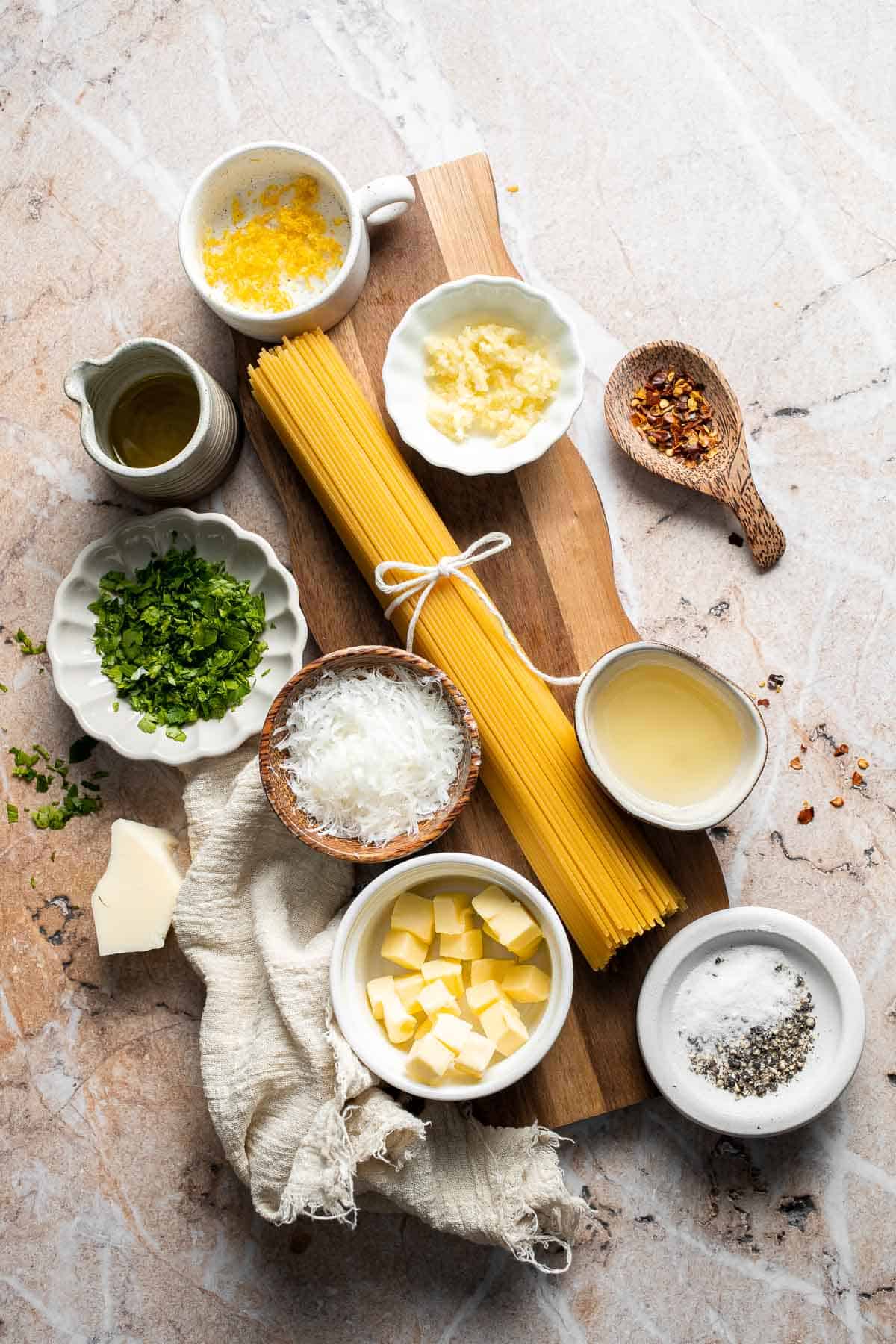Ingredients for lemon butter pasta including spaghetti, butter, garlic, Parmesan cheese, parsley, and fresh lemon.