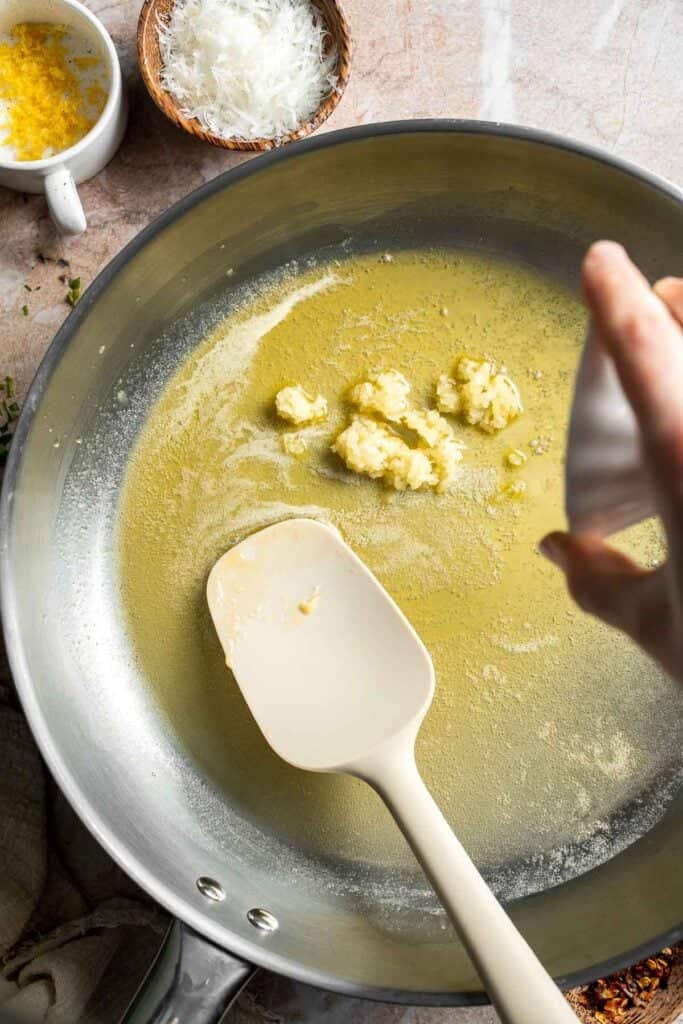 Adding minced garlic to melted butter.