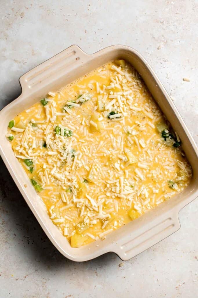 Assembled breakfast casserole with shredded cheese on top before baking. | aheadofthyme.com