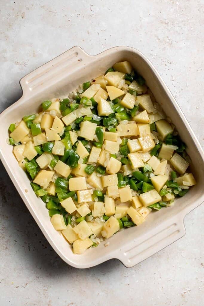 Sautéed vegetables on bottom of casserole dish. | aheadofthyme.com