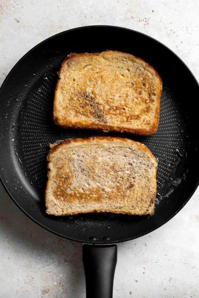 Frying two slices of French toast on a skillet. | aheadofthyme.com