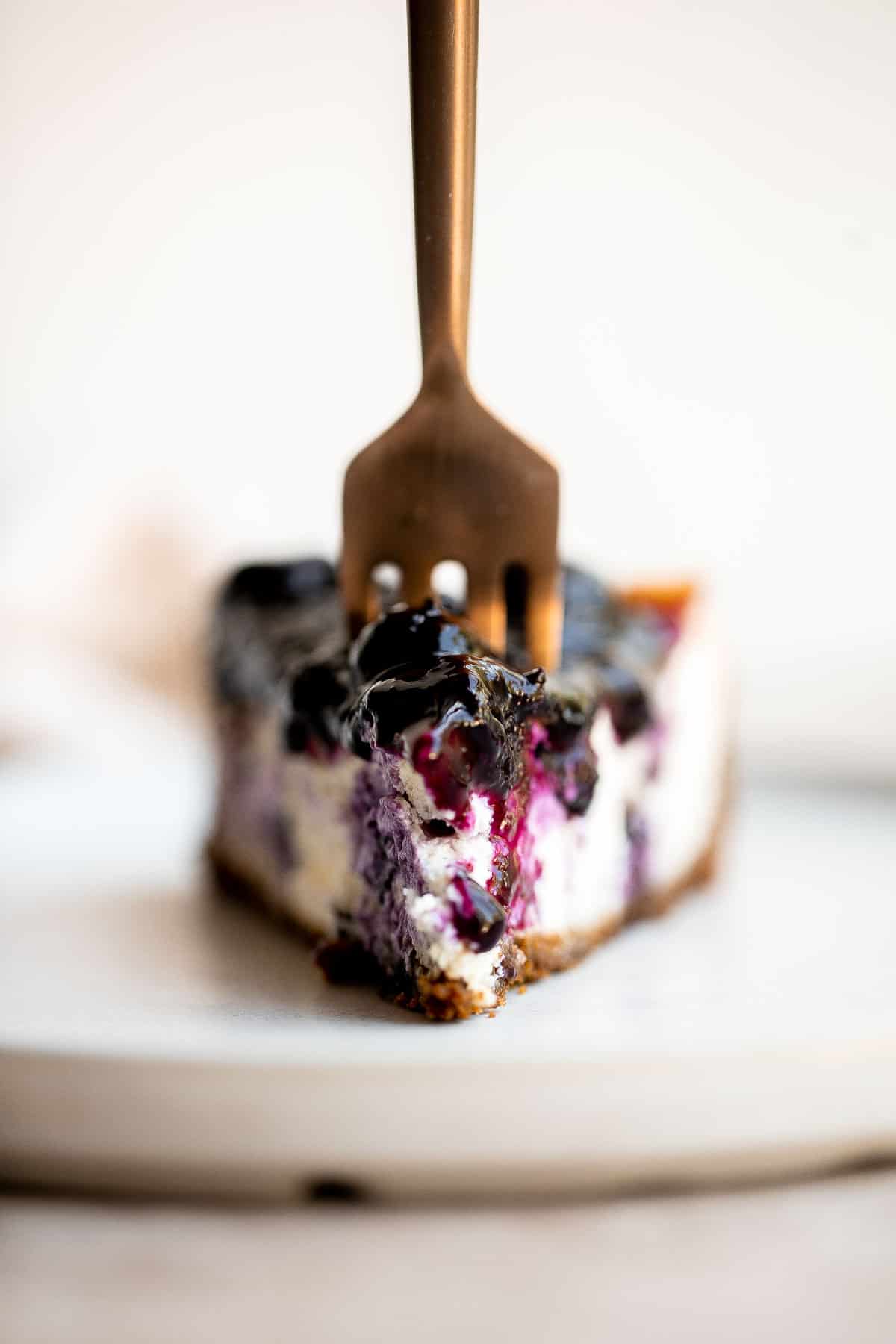 This Blueberry Cheesecake is rich, sweet, and smooth with a creamy cheesecake layer packed with blueberries and topped with sweet blueberry sauce. | aheadofthyme.com