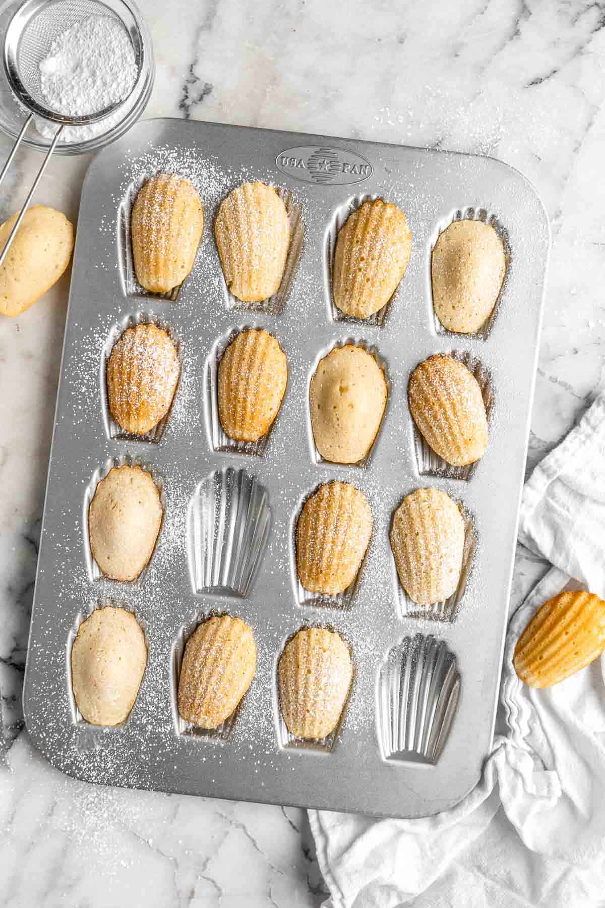 Classic Madeleines are soft spongy mini cakes with a signature shell shape and dusting of sugar on top. Making French butter cakes is easier than you think! | aheadofthyme.com