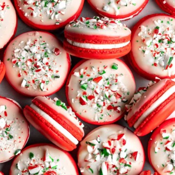 Peppermint Macarons with festive red shells, creamy peppermint buttercream, and a white chocolate candy cane topping are the ultimate Christmas cookies. | aheadofthyme.com