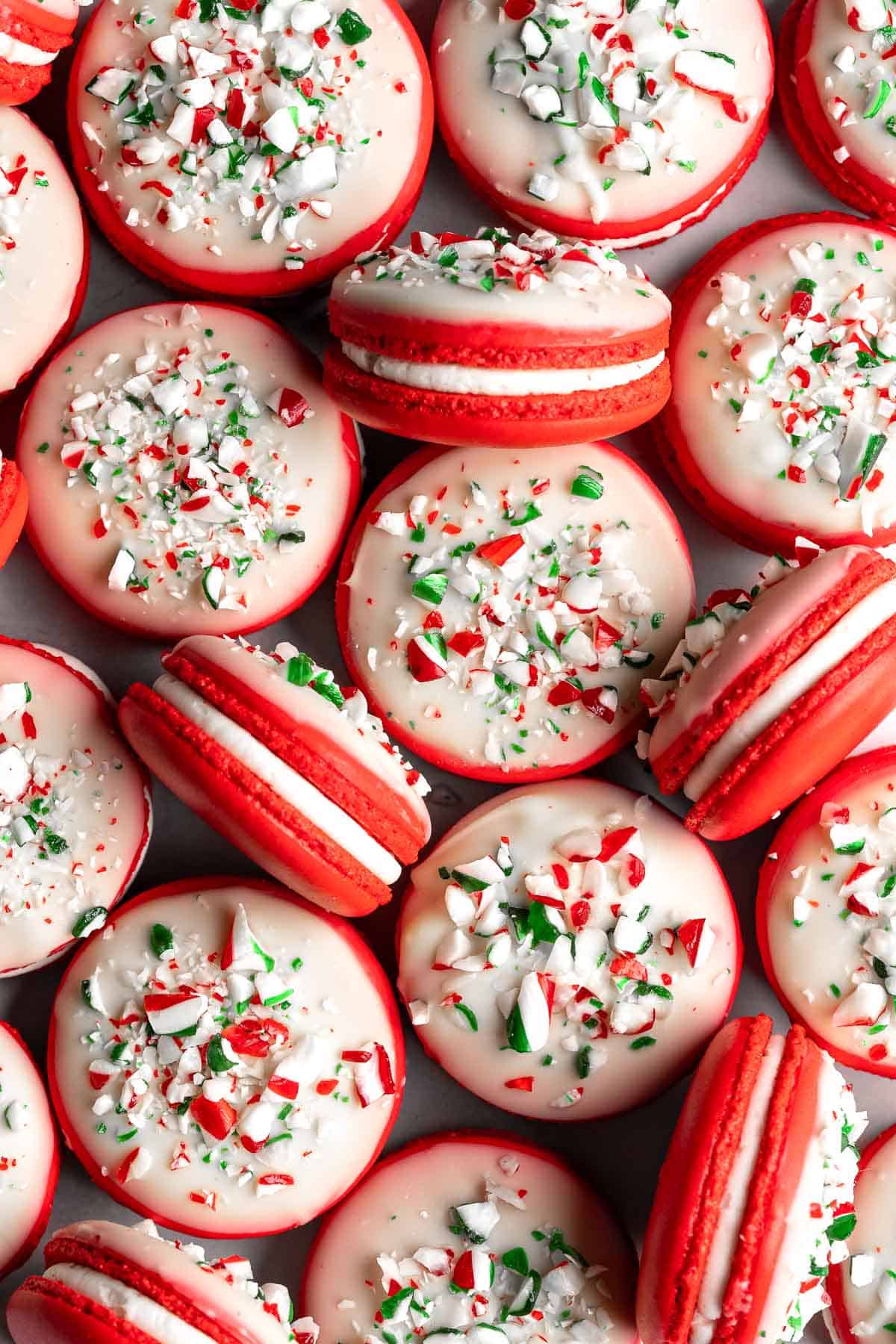 Peppermint Macarons with festive red shells, creamy peppermint buttercream, and a white chocolate candy cane topping are the ultimate Christmas cookies. | aheadofthyme.com