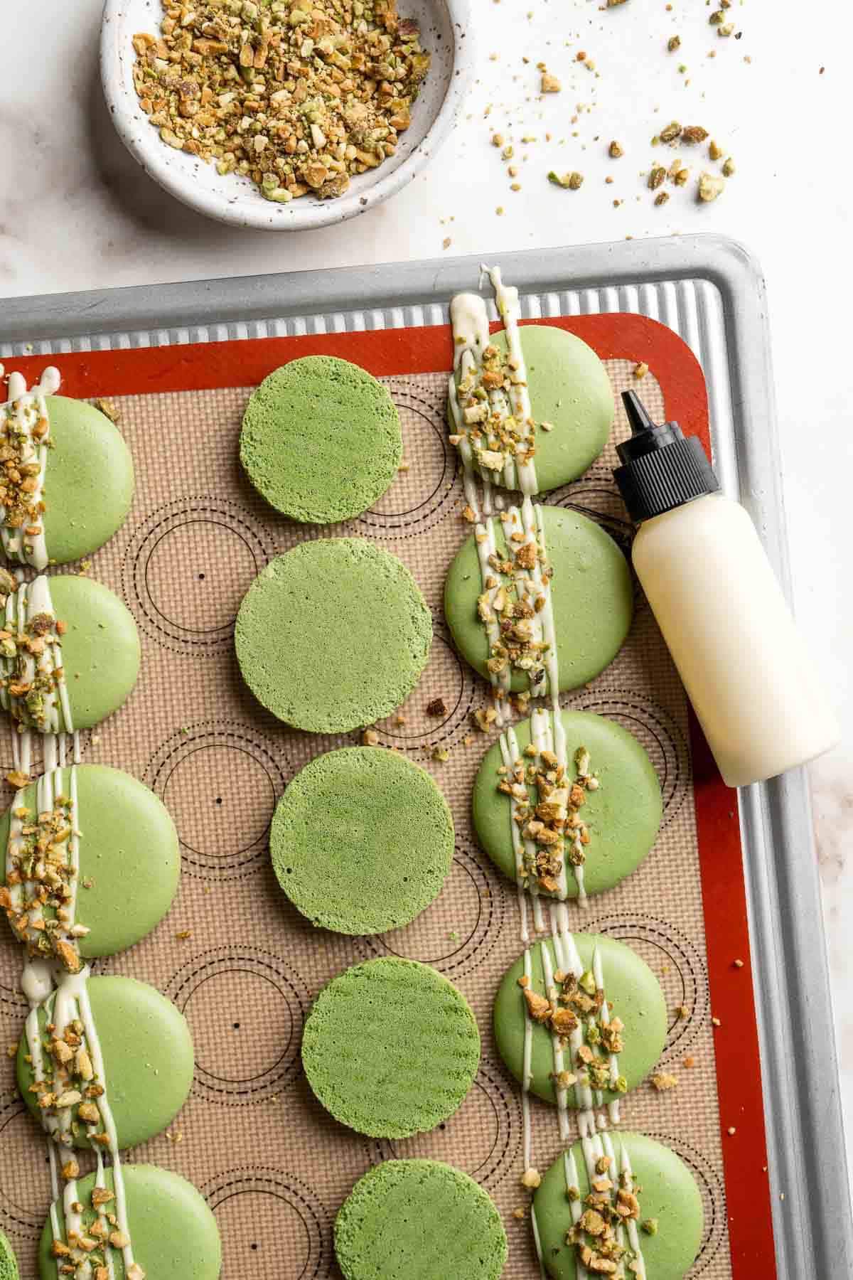 Pistachio Macarons are delicate, chewy, melt-in-your-mouth cookies filled with pistachio white chocolate ganache filling and chopped pistachios on top. | aheadofthyme.com