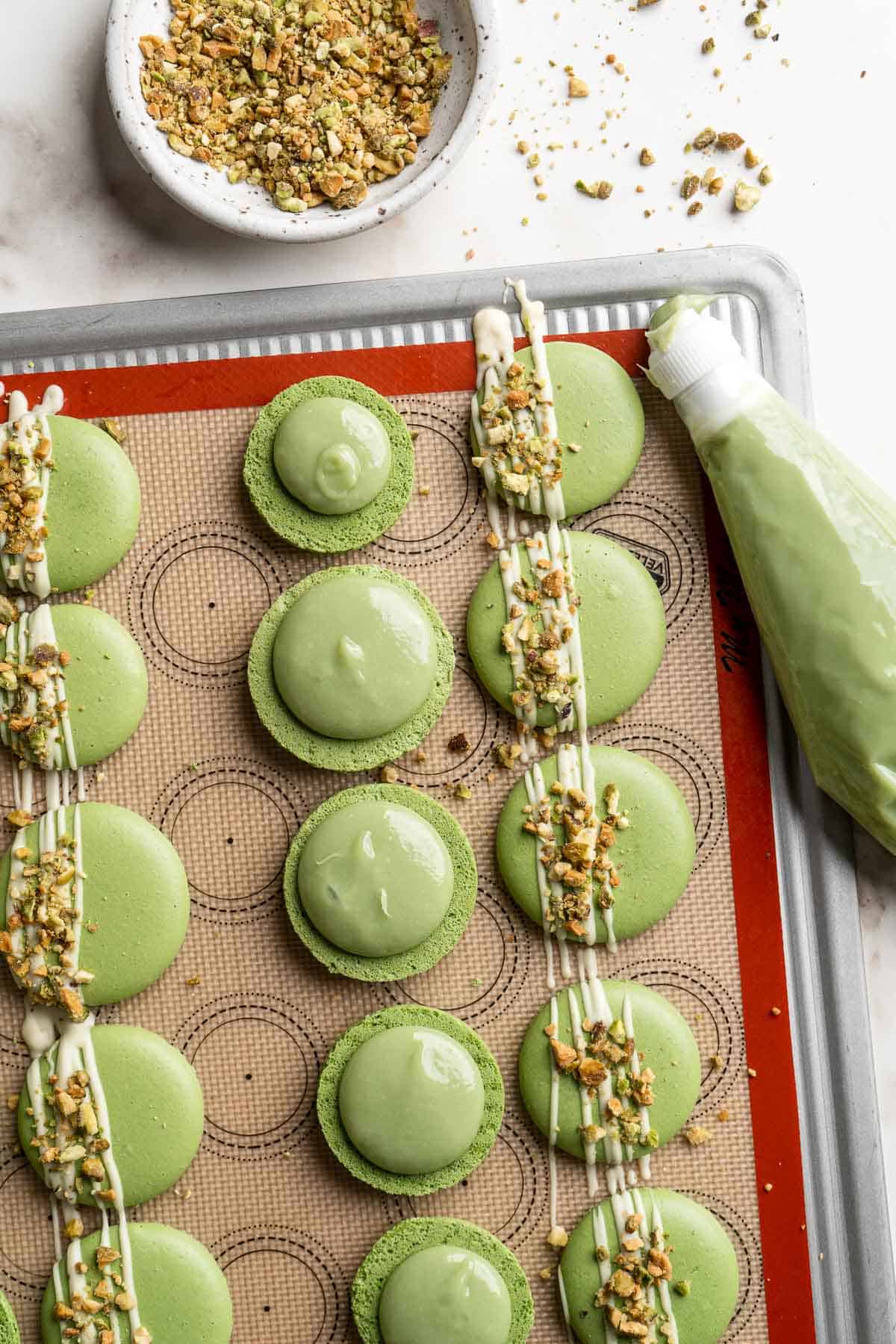 Pistachio Macarons are delicate, chewy, melt-in-your-mouth cookies filled with pistachio white chocolate ganache filling and chopped pistachios on top. | aheadofthyme.com