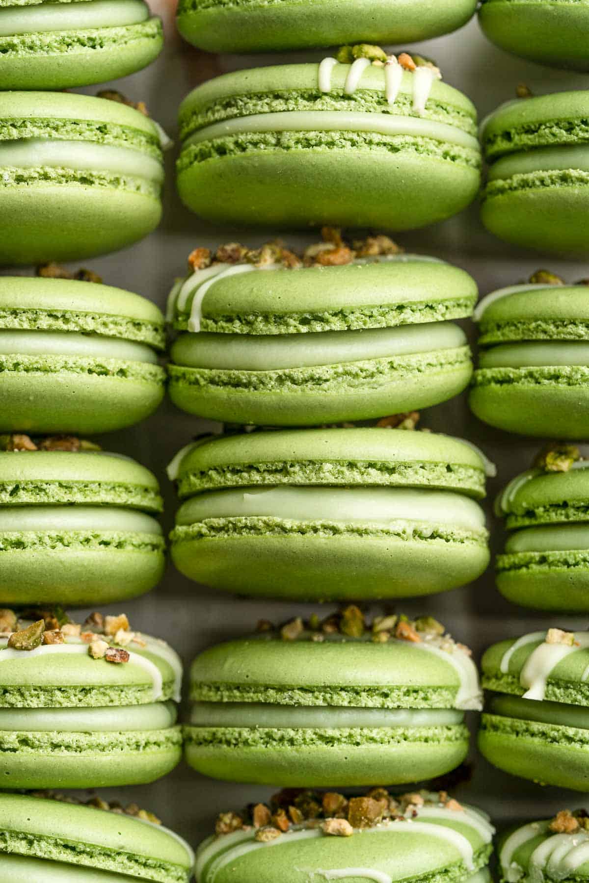 Pistachio Macarons are delicate, chewy, melt-in-your-mouth cookies filled with pistachio white chocolate ganache filling and chopped pistachios on top. | aheadofthyme.com