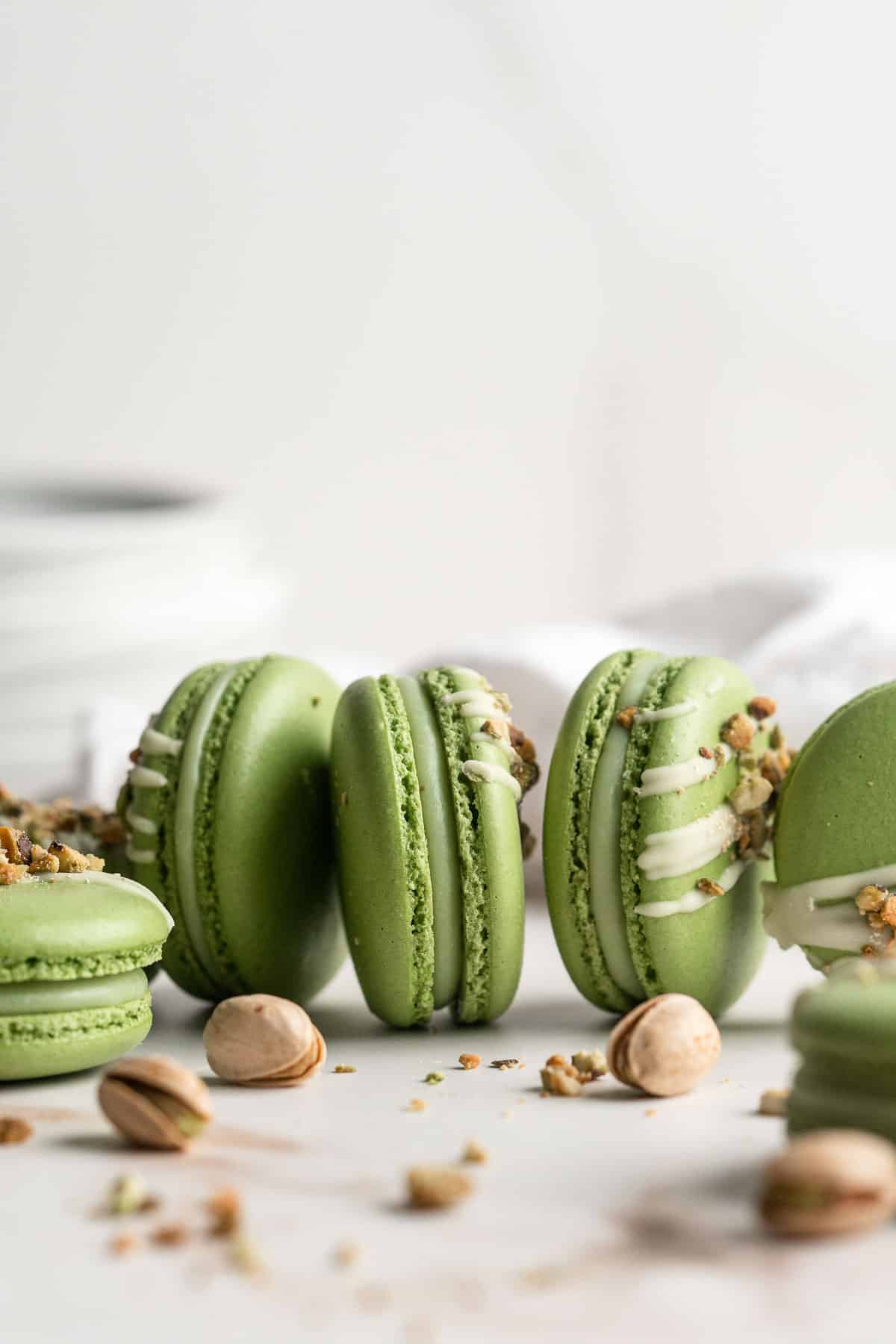 Pistachio Macarons are delicate, chewy, melt-in-your-mouth cookies filled with pistachio white chocolate ganache filling and chopped pistachios on top. | aheadofthyme.com
