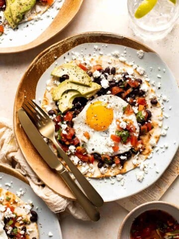 Huevos Rancheros is a classic Mexican breakfast dish that features fried eggs perched atop a bed of warm tortillas and beans and topped with salsa. | aheadofthyme.com