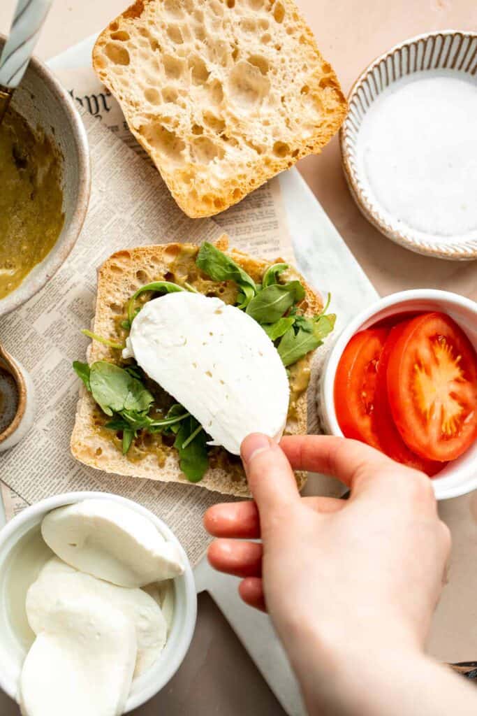 This vegetarian Caprese Sandwich is packed with layers of fresh tomatoes, mozzarella, greens, and a balsamic basil pesto sauce in between ciabatta buns. | aheadofthyme.com