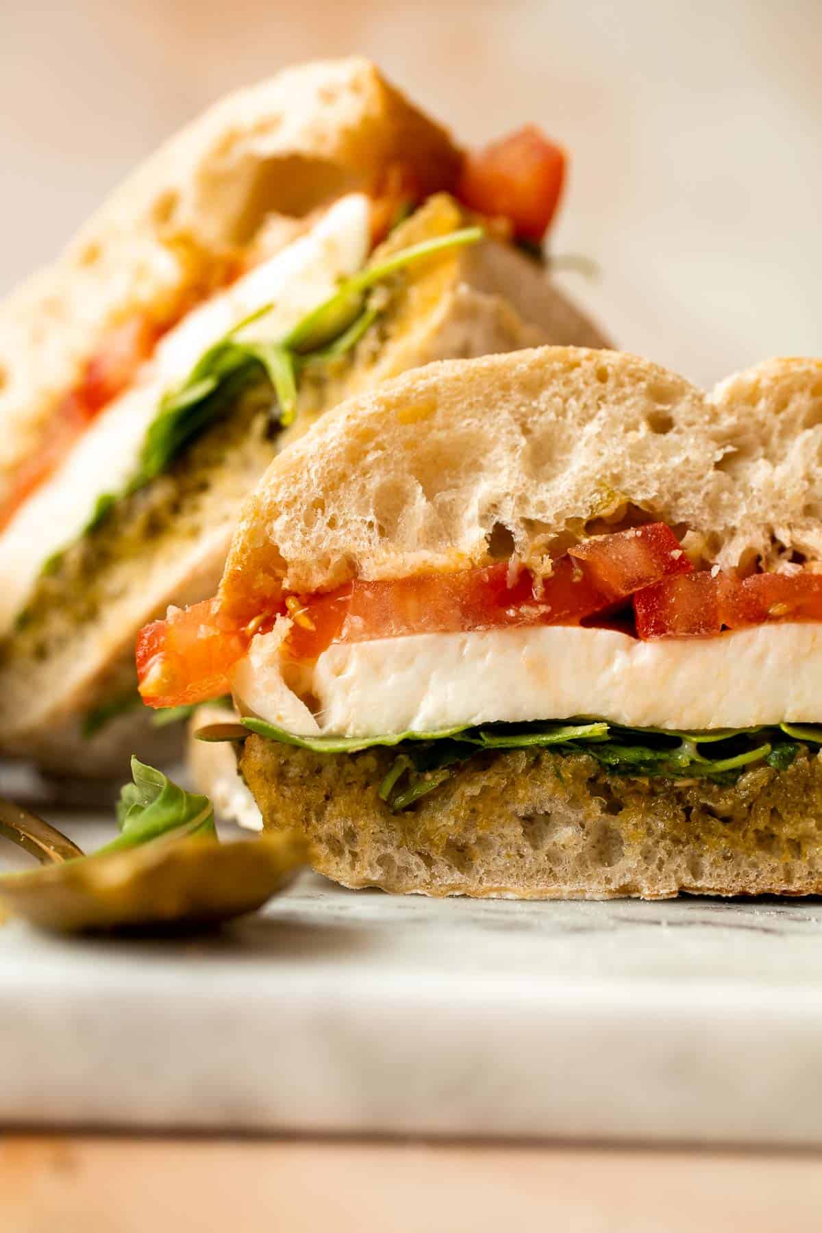 This vegetarian Caprese Sandwich is packed with layers of fresh tomatoes, mozzarella, greens, and a balsamic basil pesto sauce in between ciabatta buns. | aheadofthyme.com