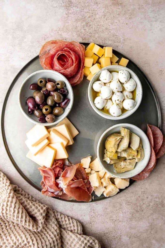 This Antipasto Platter is a show-stopping appetizer made with a variety of marinated veggies, olives, cheeses, breads, cured meats, and fresh vegetables. | aheadofthyme.com