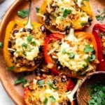 Baked vegetarian quinoa stuffed peppers topped with bubbling melted cheese and fresh parsley
