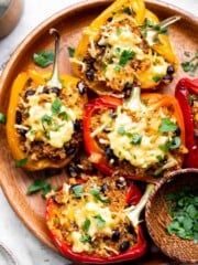 Baked vegetarian quinoa stuffed peppers topped with bubbling melted cheese and fresh parsley