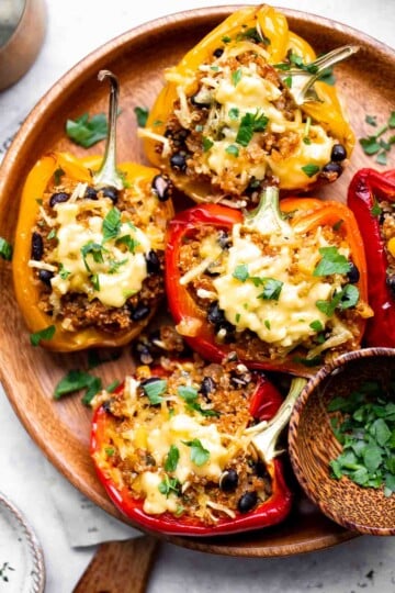 Baked vegetarian quinoa stuffed peppers topped with bubbling melted cheese and fresh parsley