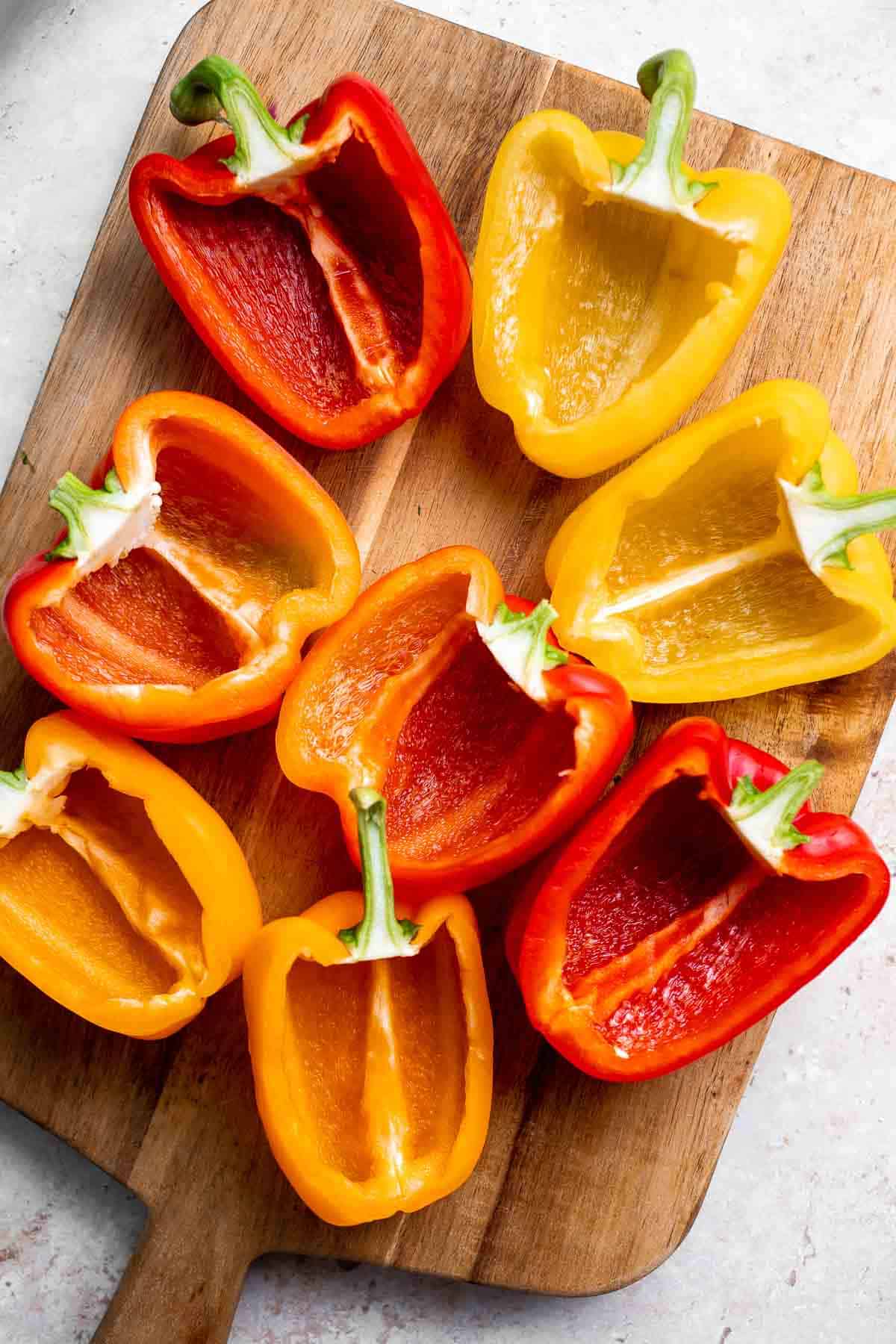Raw halved bell peppers on a cutting board