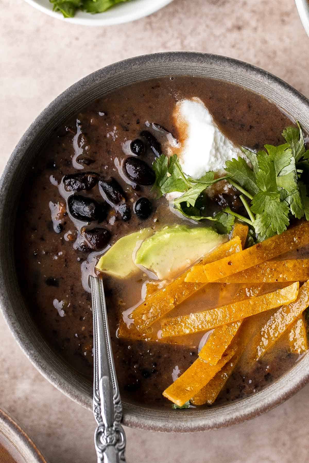 This Black Bean Soup is hearty, healthy, and cozy — everything you want in a soup! It's loaded with black beans, spices, and your favorite Mexican toppings. | aheadofthyme.com