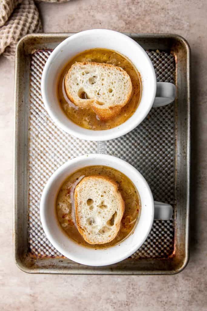 Cozy up with a warm, cheesy bowl of classic French onion soup, made with caramelized onions in a rich broth and topped with French bread and melty cheese. | aheadofthyme.com