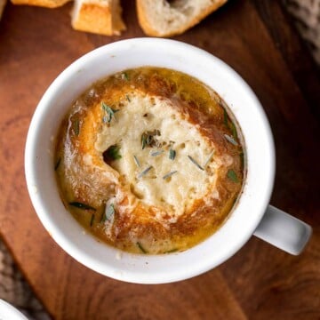 Cozy up with a warm, cheesy bowl of classic French onion soup, made with caramelized onions in a rich broth and topped with French bread and melty cheese. | aheadofthyme.com