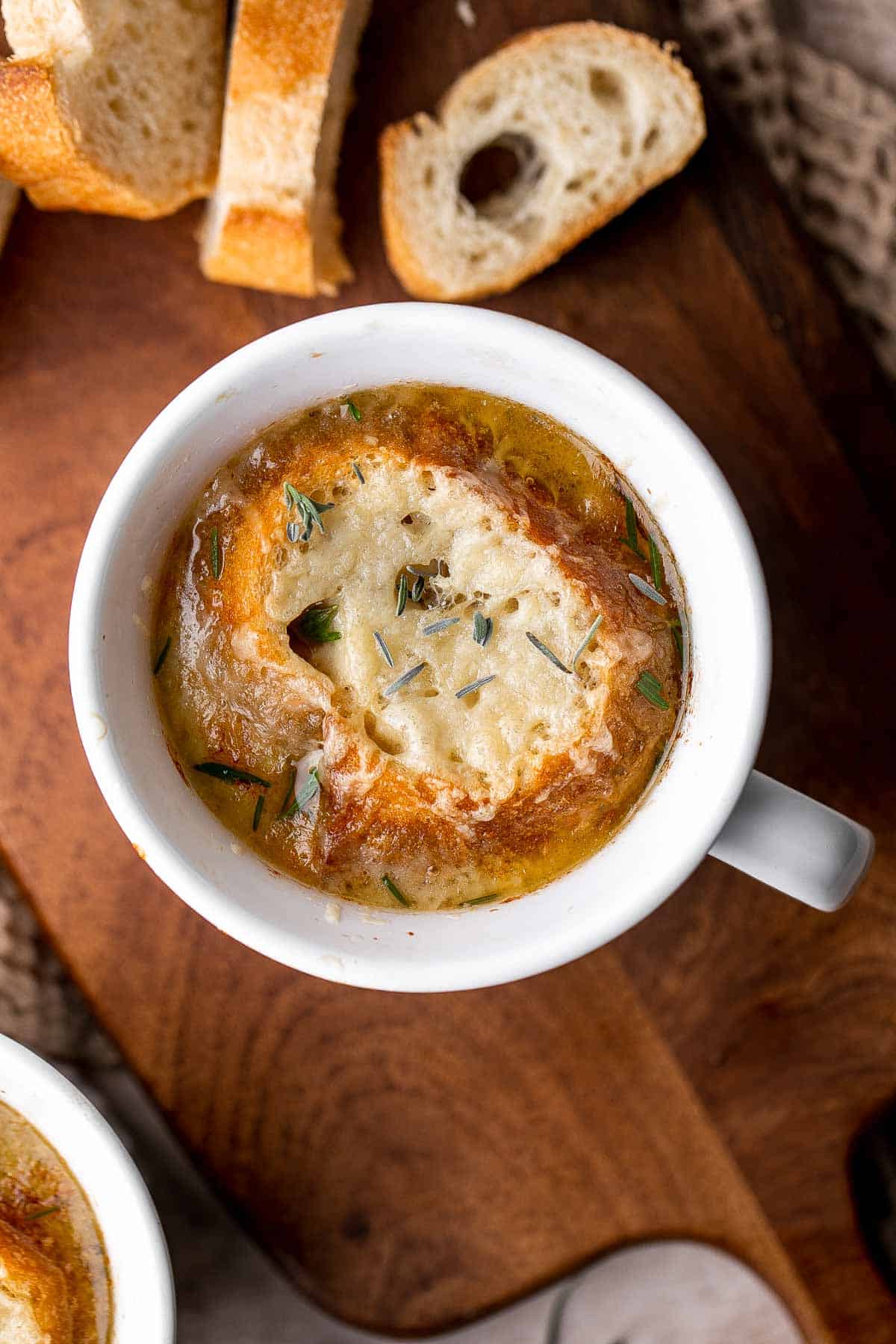 Cozy up with a warm, cheesy bowl of classic French onion soup, made with caramelized onions in a rich broth and topped with French bread and melty cheese. | aheadofthyme.com