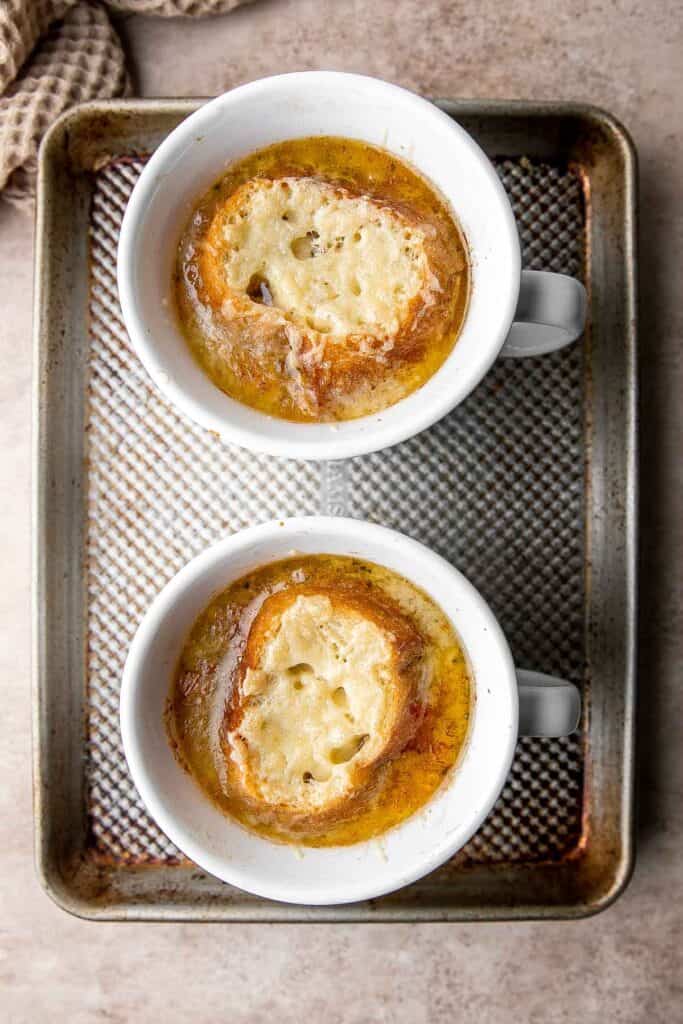 Cozy up with a warm, cheesy bowl of classic French onion soup, made with caramelized onions in a rich broth and topped with French bread and melty cheese. | aheadofthyme.com