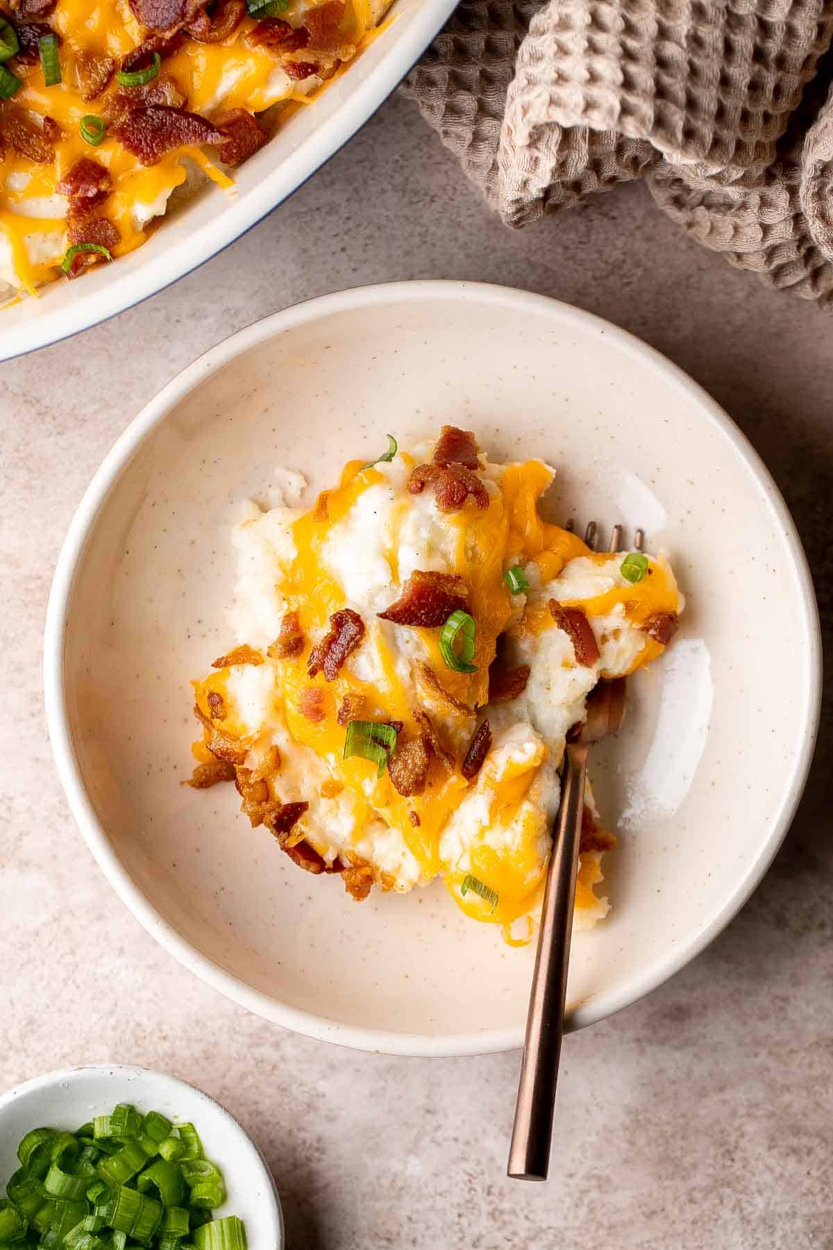 This Mashed Potato Casserole elevates an ordinary batch of creamy mashed potatoes into something divine topped with cheddar, bacon bits, and green onions. | aheadofthyme.com