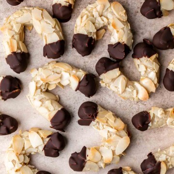Almond Horns are chewy, horseshoe-shaped crescent cookies covered in crunchy almonds and dipped in chocolate, inspired by the classic German Mandelhörnchen. | aheadofthyme.com