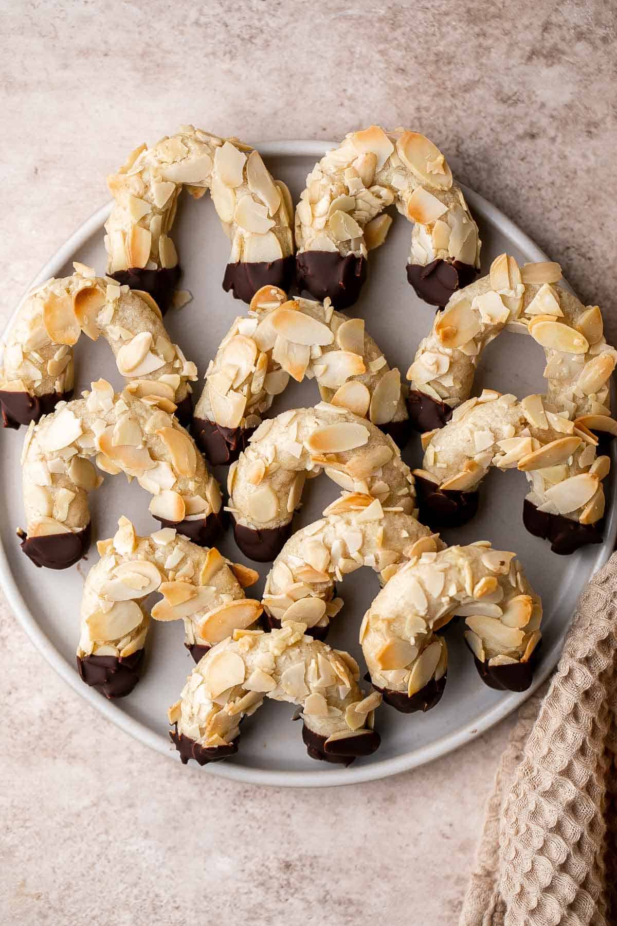 Almond Horns are chewy, horseshoe-shaped crescent cookies covered in crunchy almonds and dipped in chocolate, inspired by the classic German Mandelhörnchen. | aheadofthyme.com