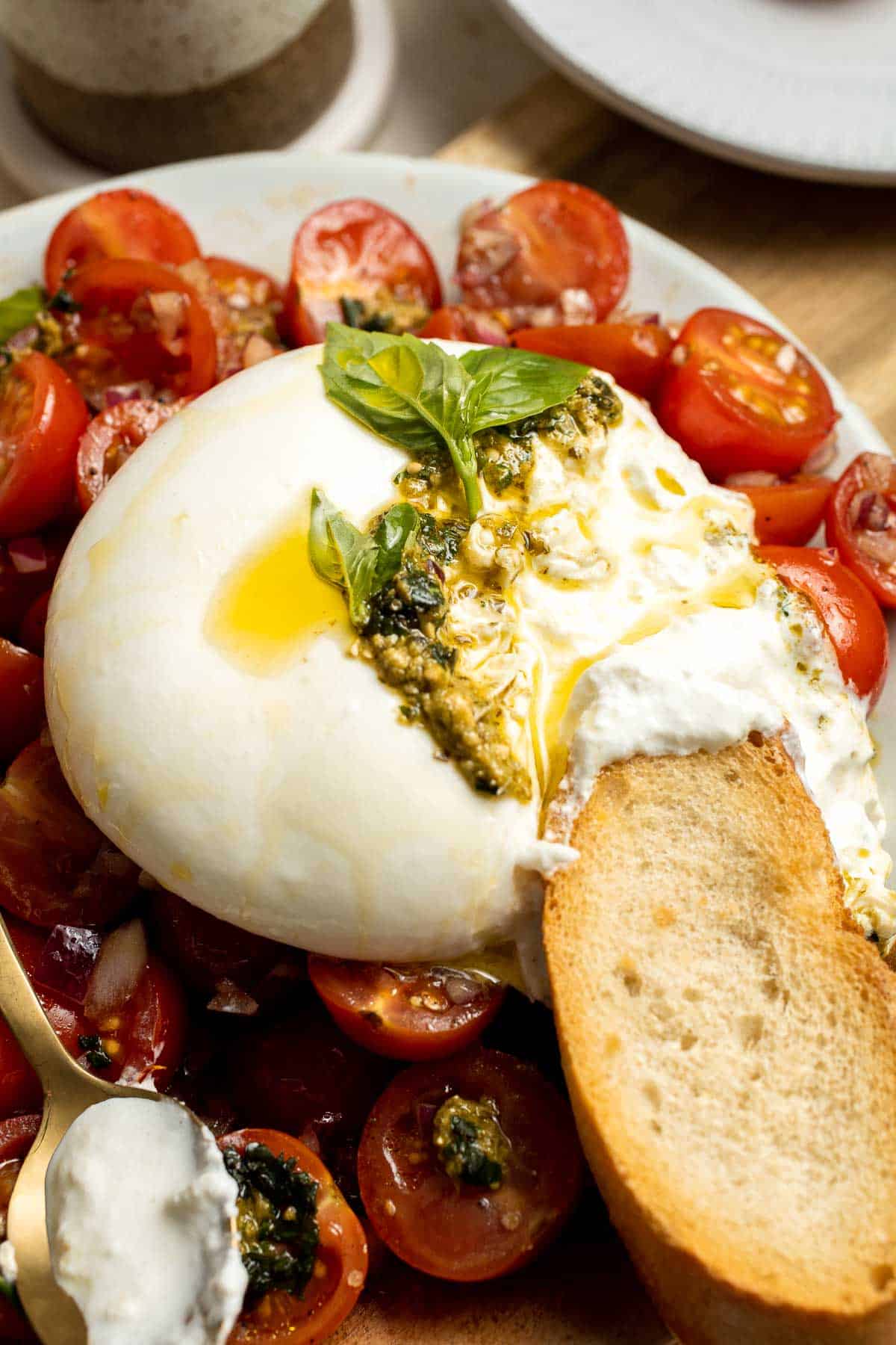 Tomato Burrata Salad is made with ultra creamy burrata over a bed of marinated tomatoes and onions and a drizzle of fresh basil pesto on top. So fresh! | aheadofthyme.com