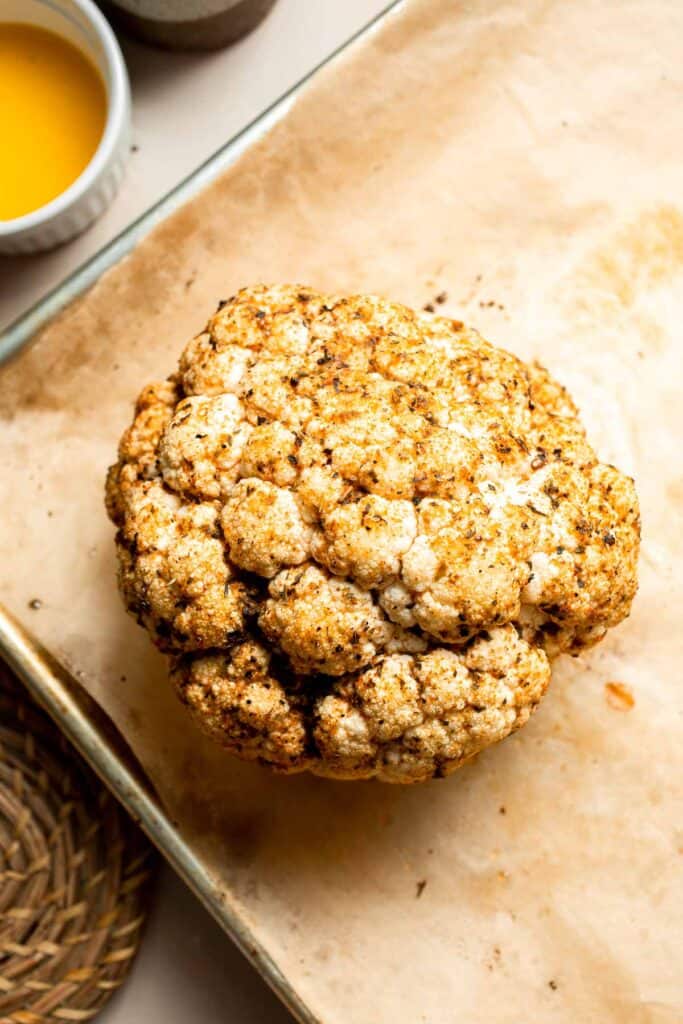 Whole Roasted Cauliflower features a flavorful crust and tender, buttery florets. It is a stunning vegetarian centerpiece that is easy to prepare. | aheadofthyme.com