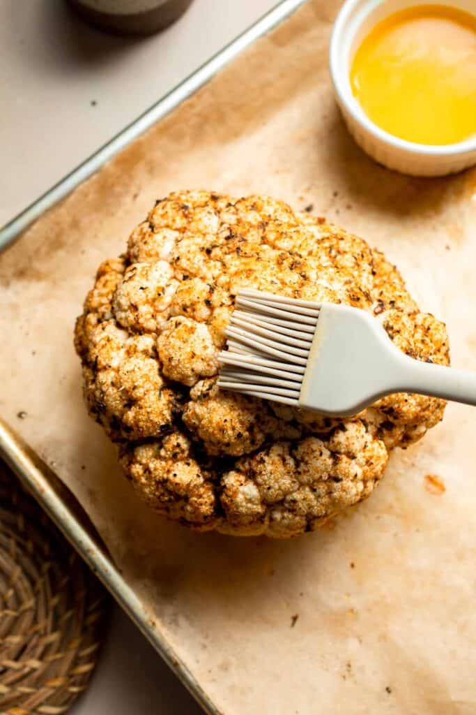 Whole Roasted Cauliflower features a flavorful crust and tender, buttery florets. It is a stunning vegetarian centerpiece that is easy to prepare. | aheadofthyme.com