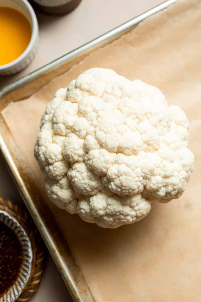Whole Roasted Cauliflower features a flavorful crust and tender, buttery florets. It is a stunning vegetarian centerpiece that is easy to prepare. | aheadofthyme.com