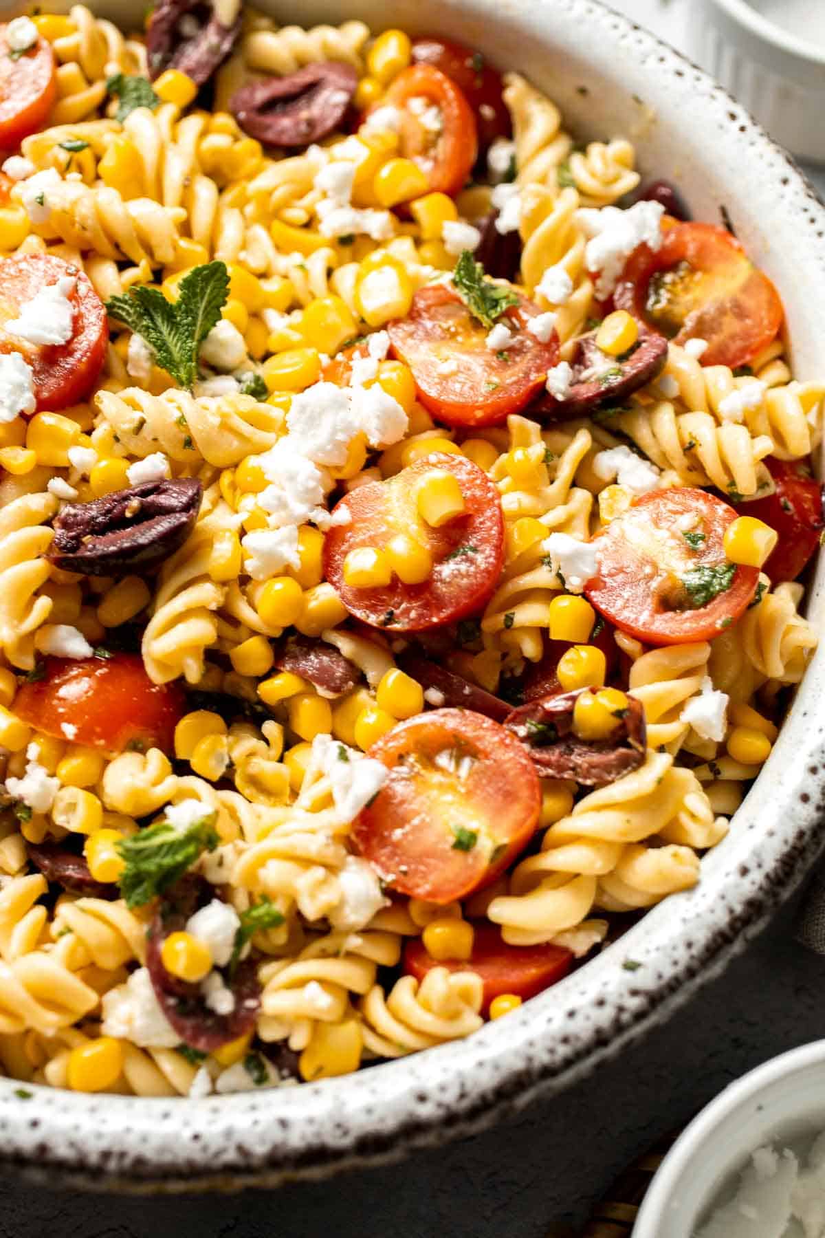 Fresh and zesty, this Corn and Tomato Pasta Salad features feta, herbs, and homemade dressing. Perfect for summer barbecues and gatherings! | aheadofthyme.com