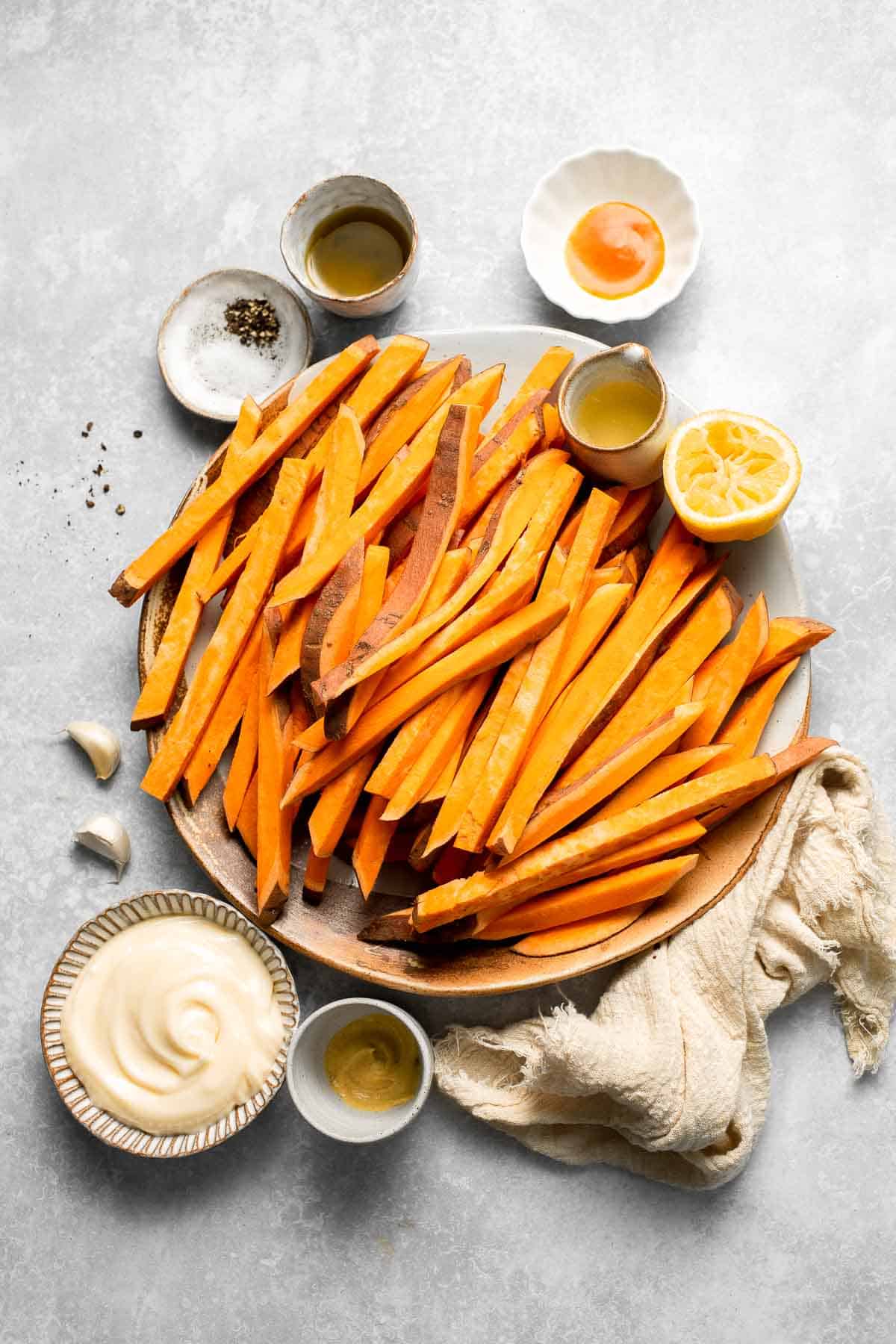 Indulge in these crispy and flavorful baked sweet potato fries, served with a creamy garlic aioli for the perfect combination of sweet and savory. | aheadofthyme.com