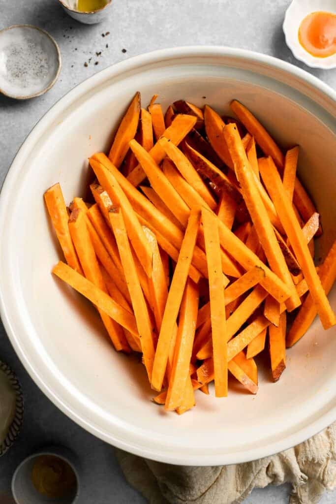 Indulge in these crispy and flavorful baked sweet potato fries, served with a creamy garlic aioli for the perfect combination of sweet and savory. | aheadofthyme.com