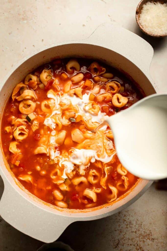 Creamy Tortellini Minestrone Soup is hearty, cozy, and loaded with veggies, beans, and cheese tortellini in a rich tomato-cream broth. | aheadofthyme.com