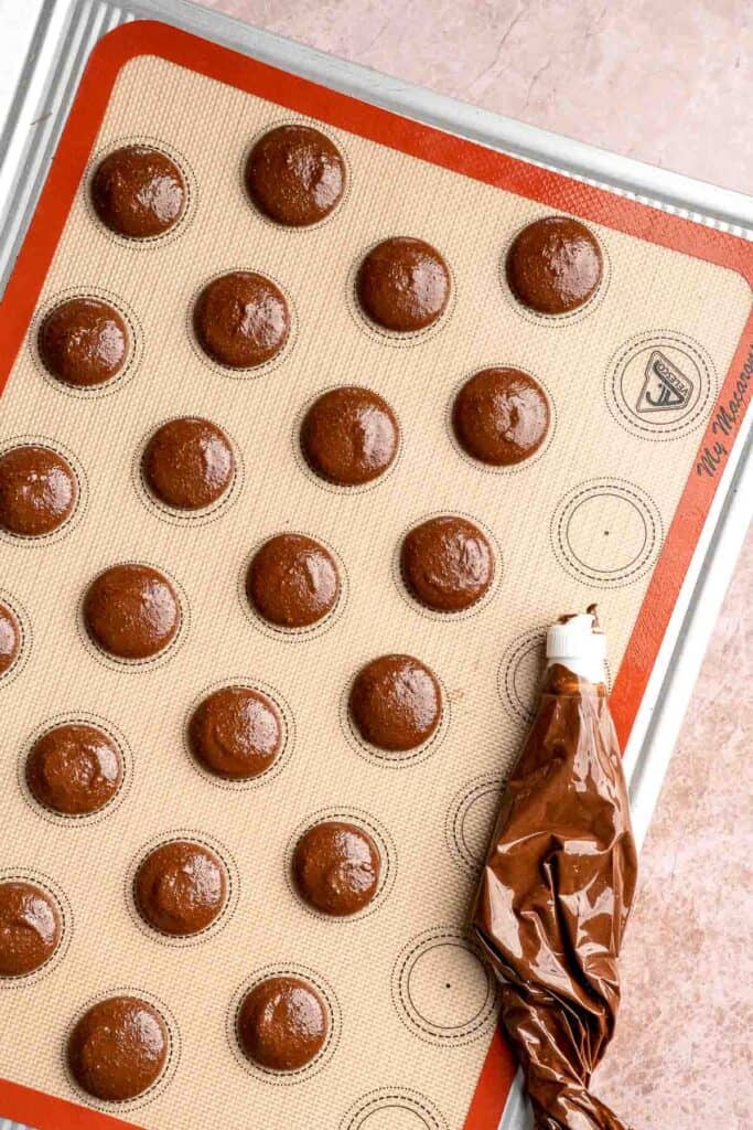 Hot chocolate macarons with cocoa shells and fluffy marshmallow filling. A cozy winter treat perfect for holiday baking and festive cookie trays. | aheadofthyme.com