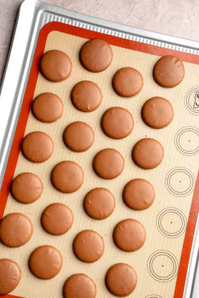 Hot chocolate macarons with cocoa shells and fluffy marshmallow filling. A cozy winter treat perfect for holiday baking and festive cookie trays. | aheadofthyme.com