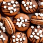 Hot chocolate macarons with cocoa shells and fluffy marshmallow filling. A cozy winter treat perfect for holiday baking and festive cookie trays. | aheadofthyme.com