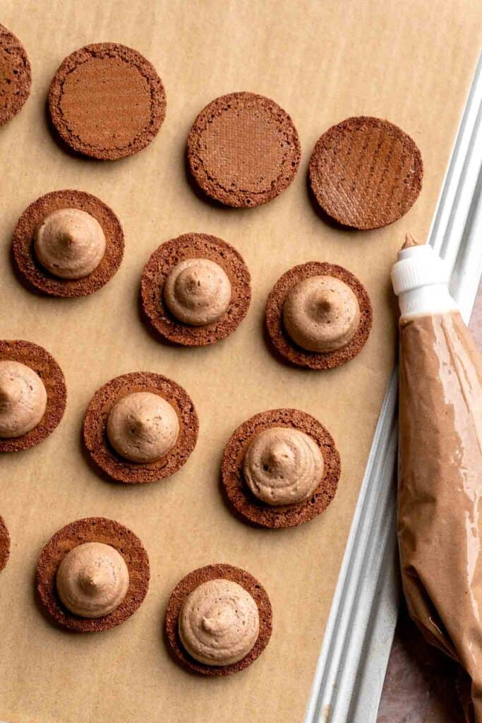 Hot chocolate macarons with cocoa shells and fluffy marshmallow filling. A cozy winter treat perfect for holiday baking and festive cookie trays. | aheadofthyme.com