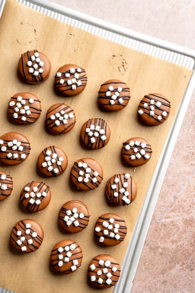 Hot chocolate macarons with cocoa shells and fluffy marshmallow filling. A cozy winter treat perfect for holiday baking and festive cookie trays. | aheadofthyme.com