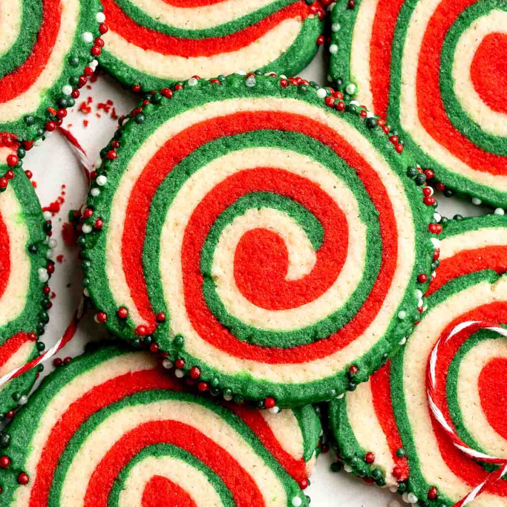 Peppermint pinwheel cookies with red, green, and white swirled dough rolled in festive sprinkles. A fun slice and bake Christmas cookie. | aheadofthyme.com