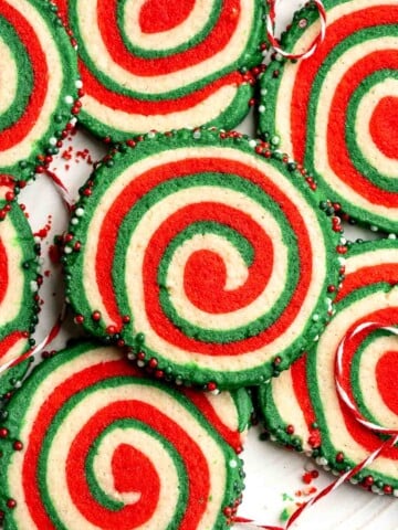 Peppermint pinwheel cookies with red, green, and white swirled dough rolled in festive sprinkles. A fun slice and bake Christmas cookie. | aheadofthyme.com