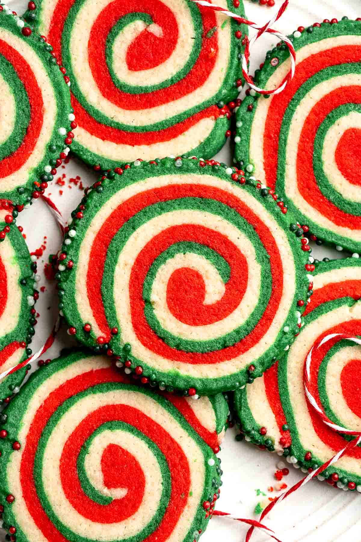 Peppermint pinwheel cookies with red, green, and white swirled dough rolled in festive sprinkles. A fun slice and bake Christmas cookie. | aheadofthyme.com