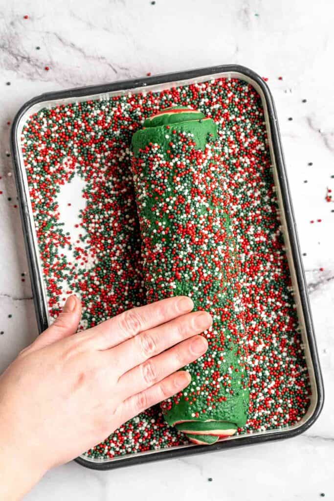 Peppermint pinwheel cookies with red, green, and white swirled dough rolled in festive sprinkles. A fun slice and bake Christmas cookie. | aheadofthyme.com