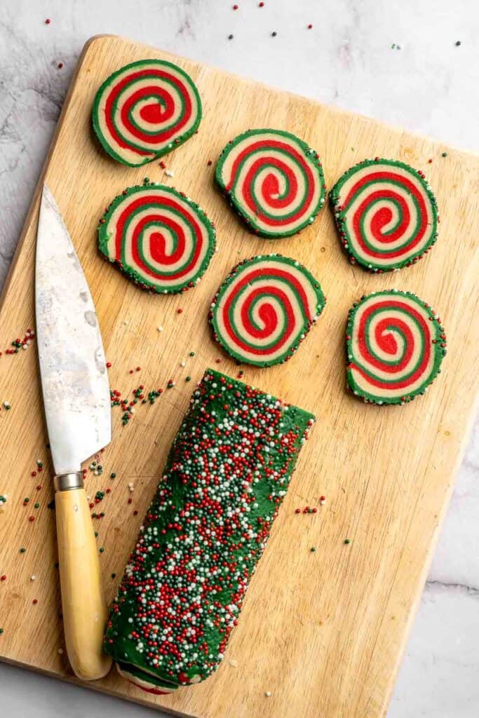 Peppermint pinwheel cookies with red, green, and white swirled dough rolled in festive sprinkles. A fun slice and bake Christmas cookie. | aheadofthyme.com