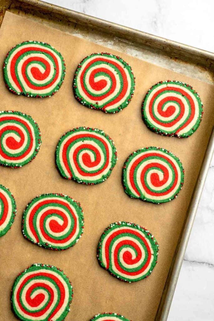 Peppermint pinwheel cookies with red, green, and white swirled dough rolled in festive sprinkles. A fun slice and bake Christmas cookie. | aheadofthyme.com