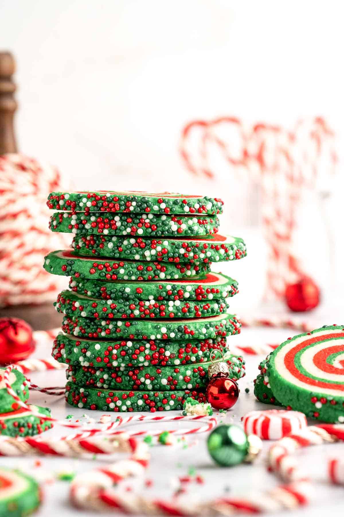 Peppermint pinwheel cookies with red, green, and white swirled dough rolled in festive sprinkles. A fun slice and bake Christmas cookie. | aheadofthyme.com
